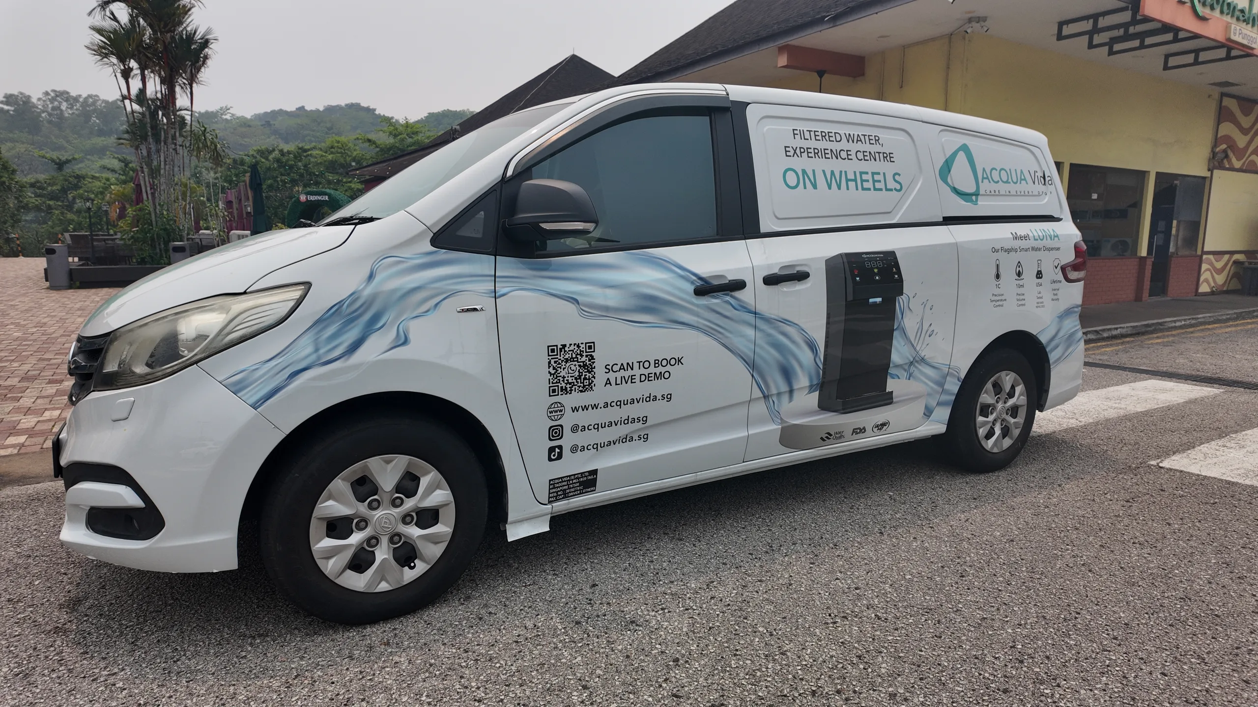 The Acqua Vida mobile showroom van, parked outside, with its full livery visible: the ACQUA Vida wordmark, 'Filtered Water Experience Centre On Wheels', a panel reading 'Meet LUNA, Our Flagship Smart Water Dispenser', and a QR code to scan and book a live demo